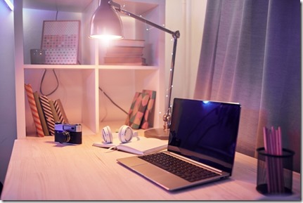 Image of workplace with laptop computer note pad and camera are on the table with electric lamp at domestic room