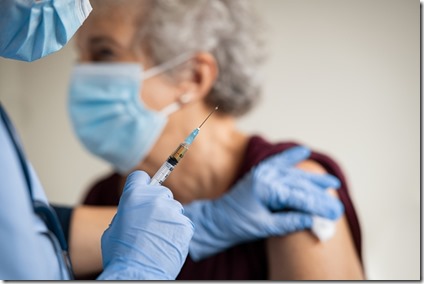 Doctor makes vaccination to senior woman with surgical mask