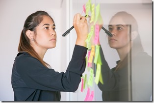 Young Latin businesswoman writing on sticker with marker