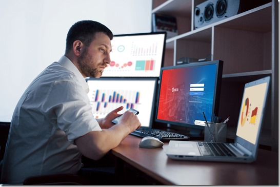 Busy working day. Close-up of young businessman looking at monitor while sitting at the desk in creative office