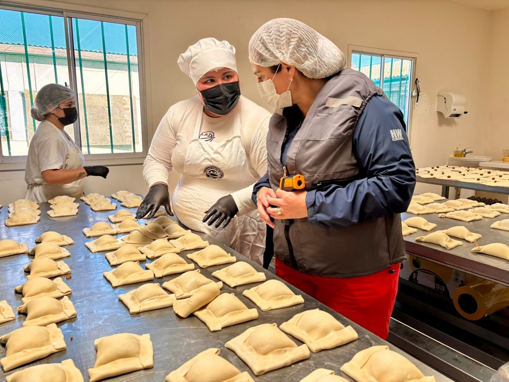 Autoridad sanitaria inspeccionando condiciones de higiene en una fábrica de empanadas