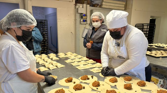 Autoridad sanitaria inspeccionando condiciones de higiene en una fábrica de empanadas